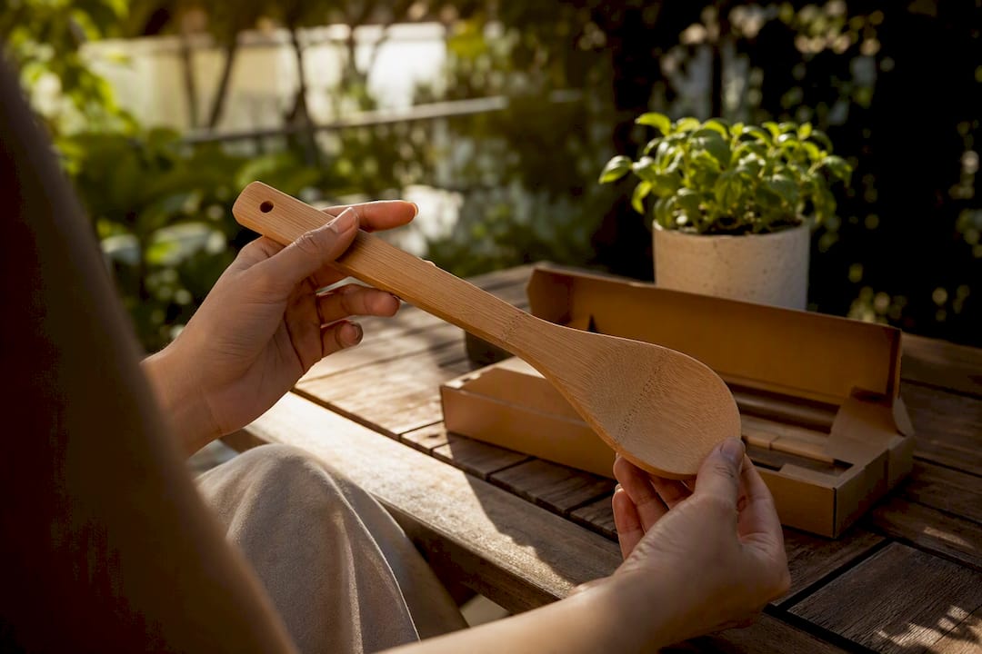 Hands holding bamboo kitchen utensil in natural kitchen