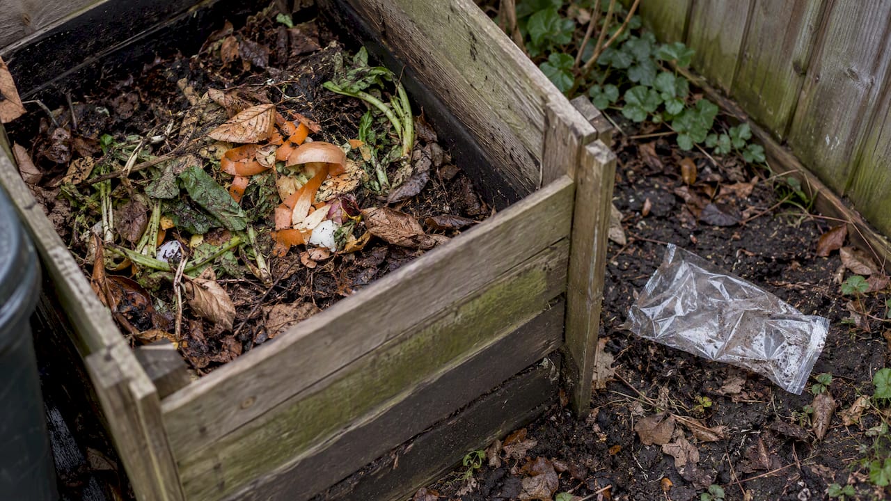 Food scraps compost beside an intact plastic wrapper